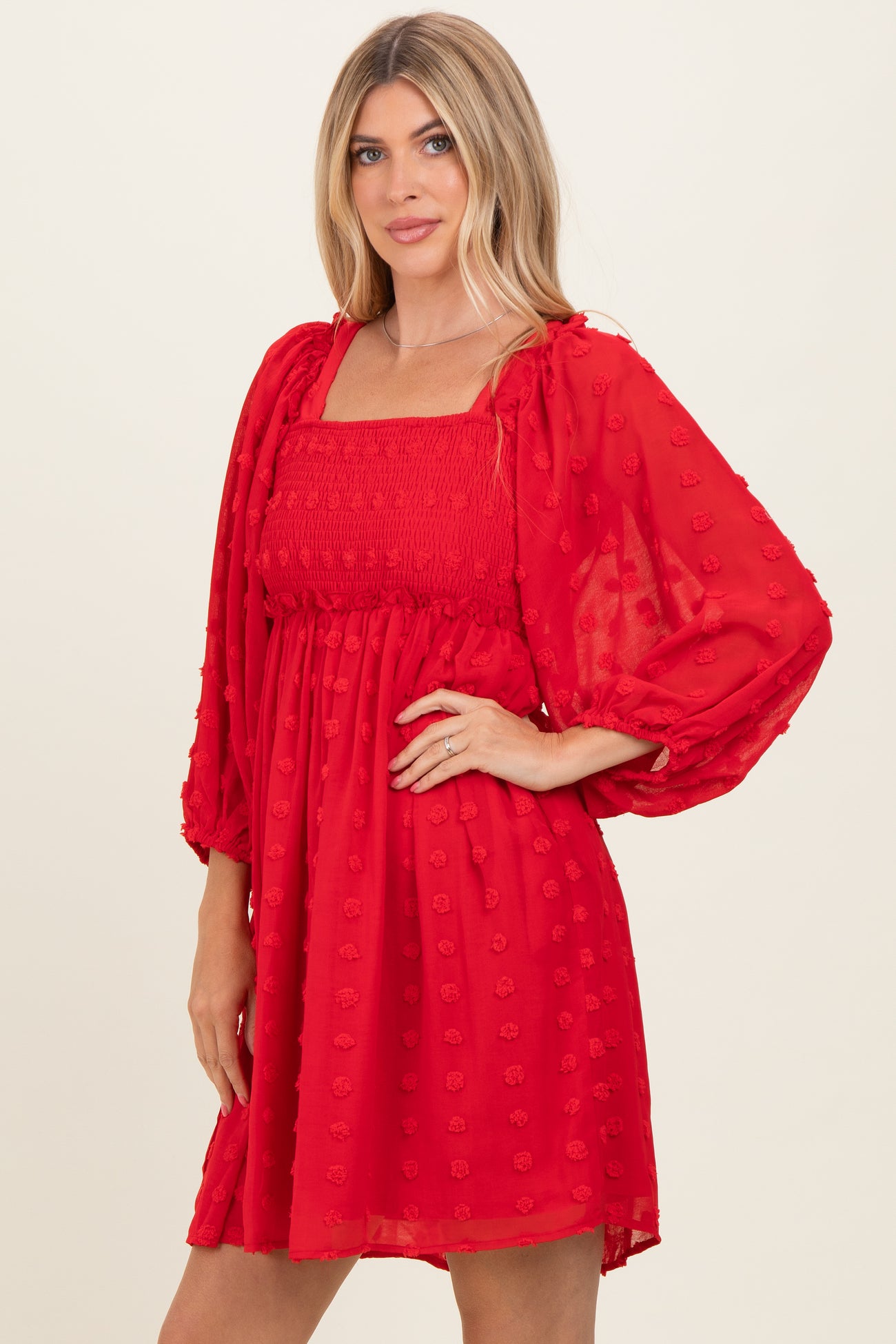 woman wearing a red puff sleeve mini dress with a square neckline and textured floral details