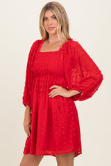 woman wearing a red puff sleeve mini dress with a square neckline and textured floral details