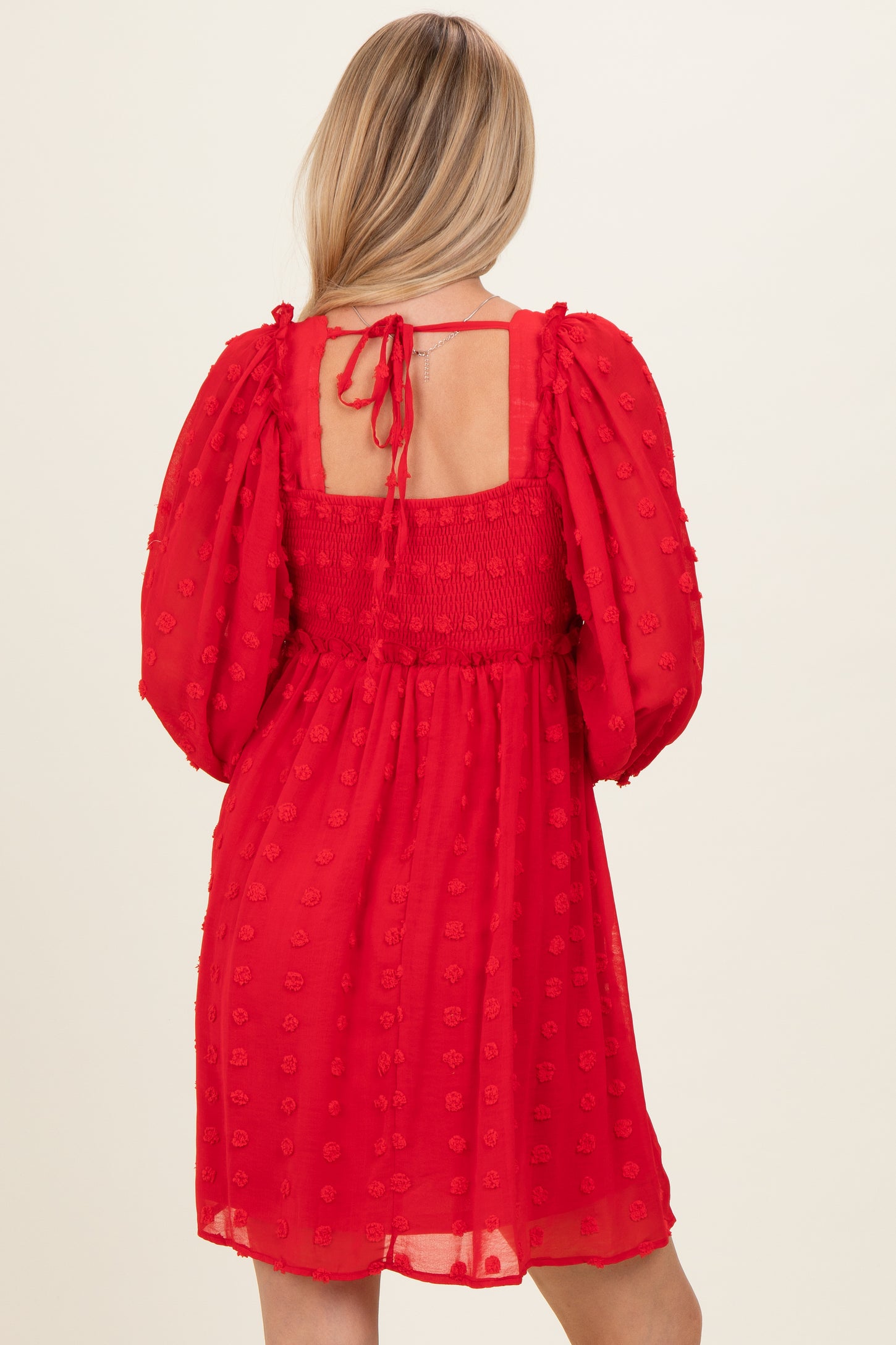 woman wearing a red puff sleeve mini dress with a smocked bodice and back tie detail