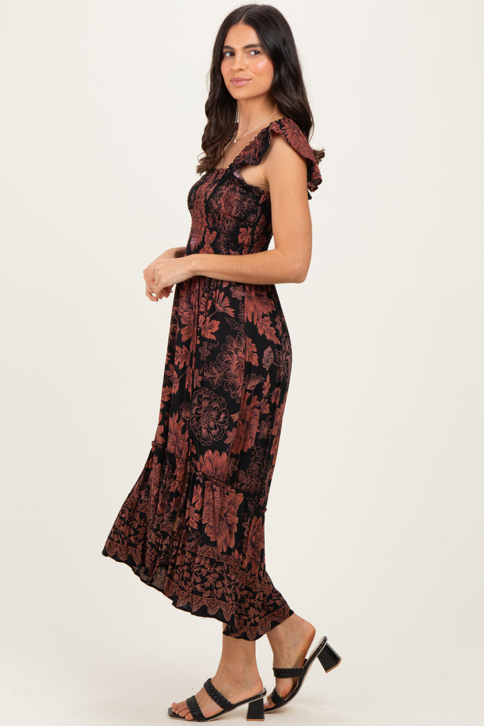 woman wearing a black and rust floral midi dress with ruffled straps and a flowy hem, posed sideways