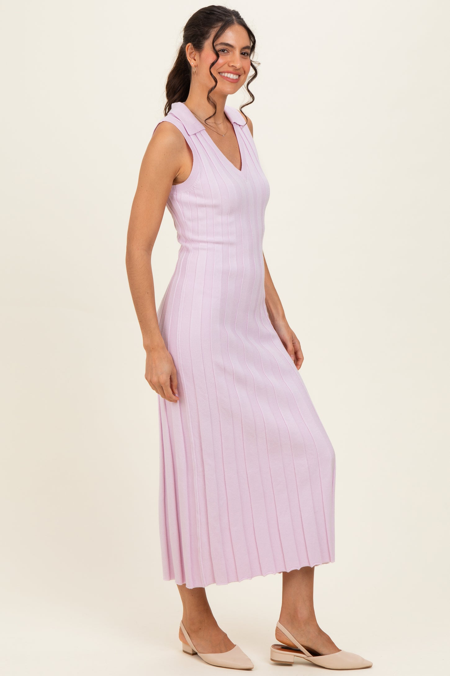 woman wearing a light pink sleeveless ribbed midi dress with a v-neckline and a fitted silhouette
