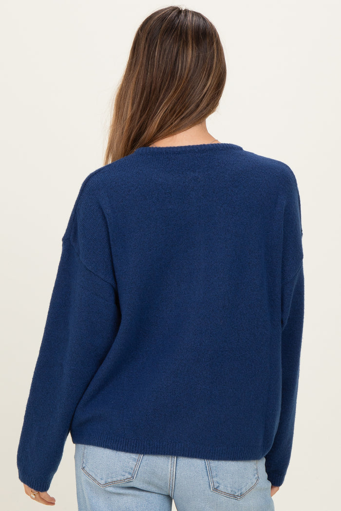 woman wearing a navy blue oversized maternity sweater, seen from the back, paired with light blue jeans