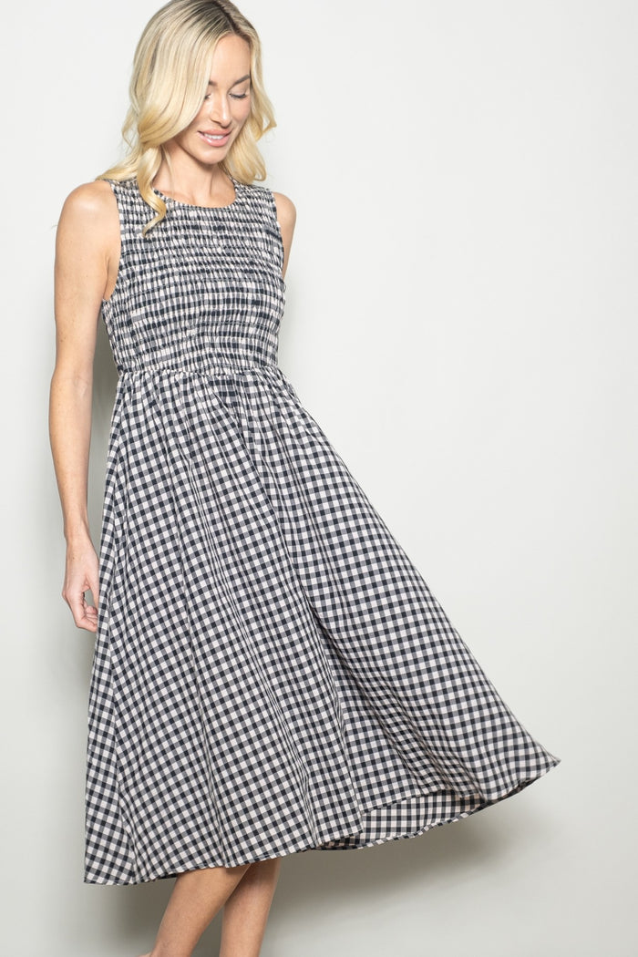 woman wearing a black and white gingham sleeveless midi dress with a smocked bodice and flowing skirt