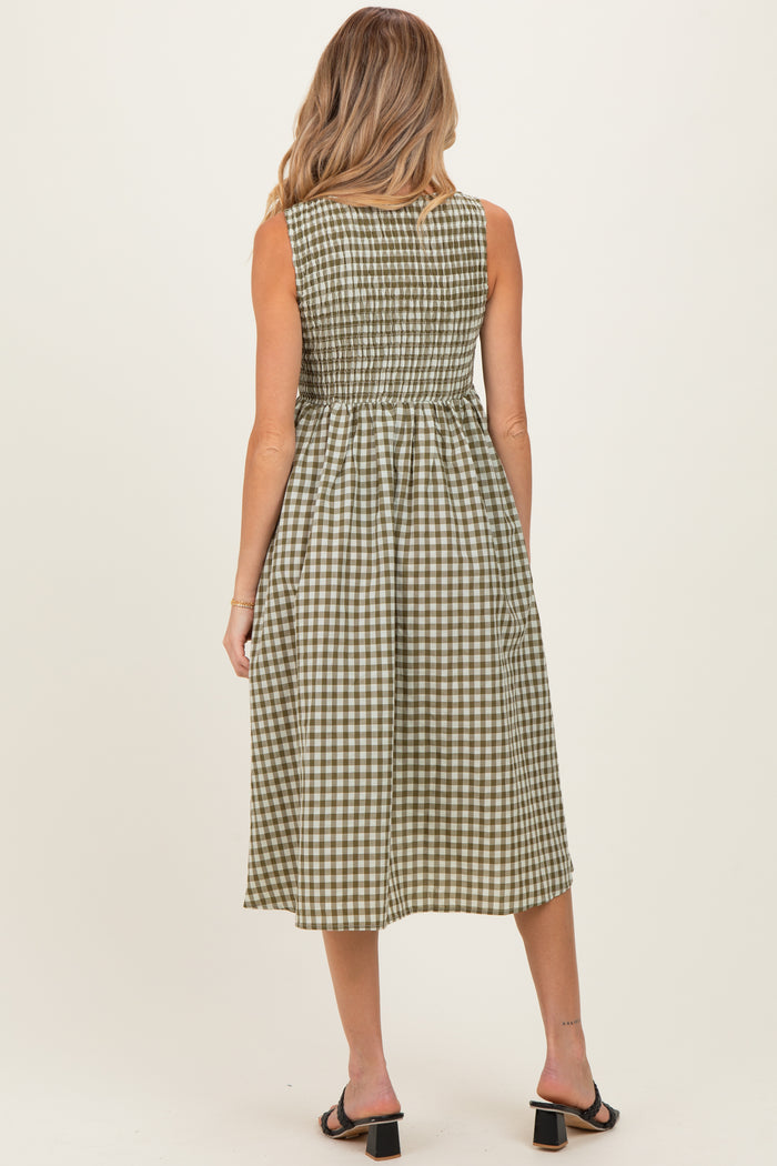 woman wearing a green and white gingham maternity dress with a fitted bodice and flowing skirt, showing her back