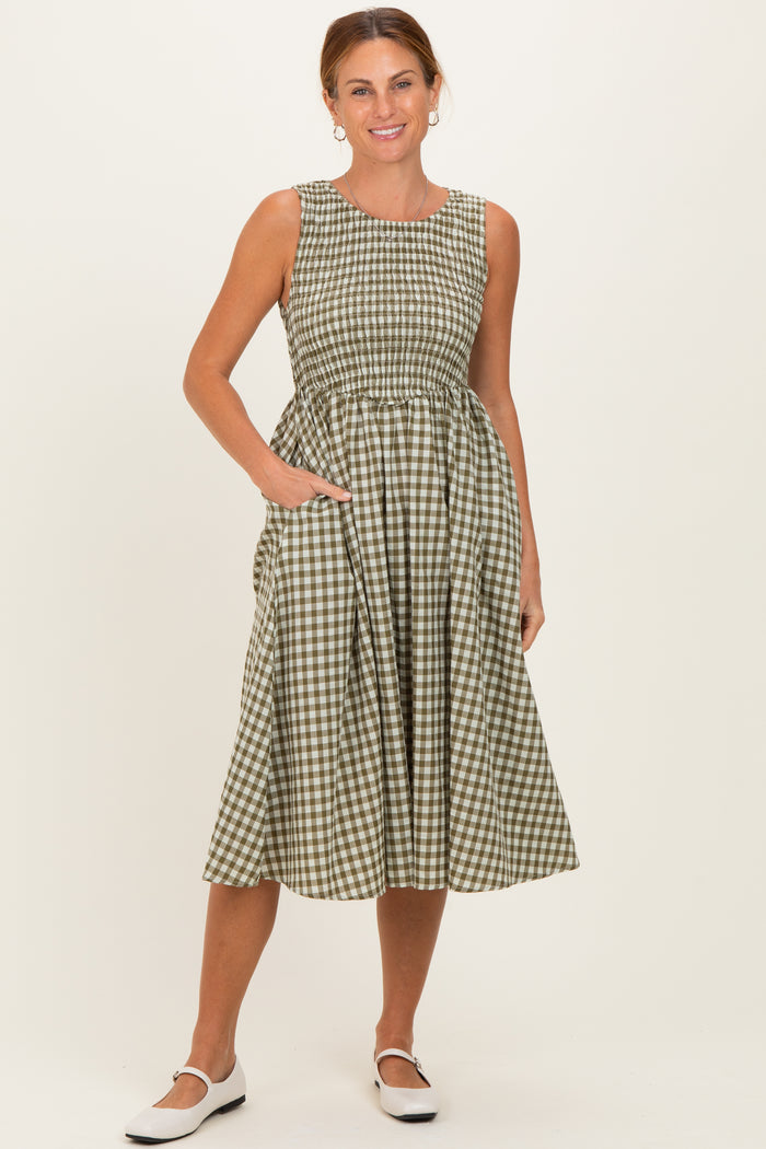 woman wearing a green and white gingham midi dress with a fitted bodice and pockets