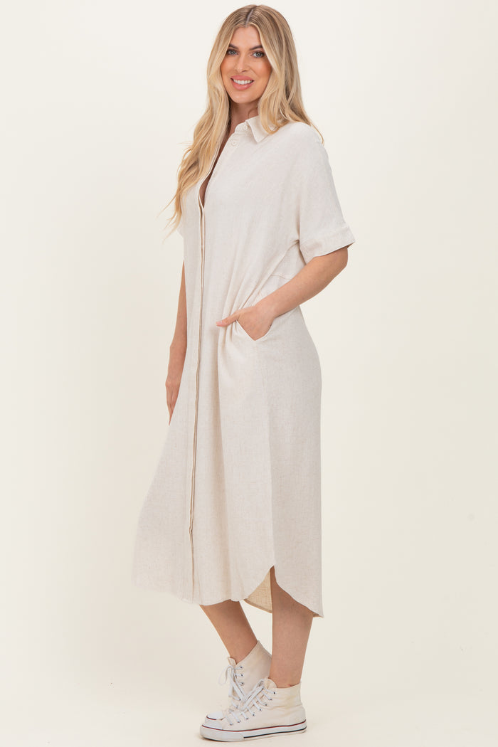 woman wearing a light beige short sleeve button-up dress with side pockets and a high-low hem, paired with white sneakers