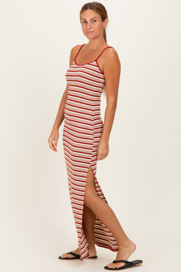 woman wearing a red and white striped maxi dress with side slits and adjustable straps, standing in profile