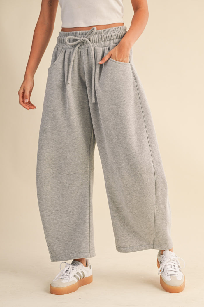 woman wearing gray wide-leg sweatpants with an elastic waistband and side pockets, paired with white sneakers