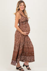 woman wearing a brown patterned maternity maxi dress and holding her baby bump