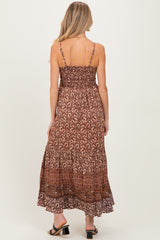 woman wearing a brown patterned maternity maxi dress with adjustable straps and a smocked bodice, showing her back