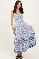 woman wearing a blue and white floral maxi dress with a twist front and spaghetti straps