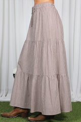woman wearing a brown and cream checkered tiered maxi skirt with an elastic waistband and drawstring detail