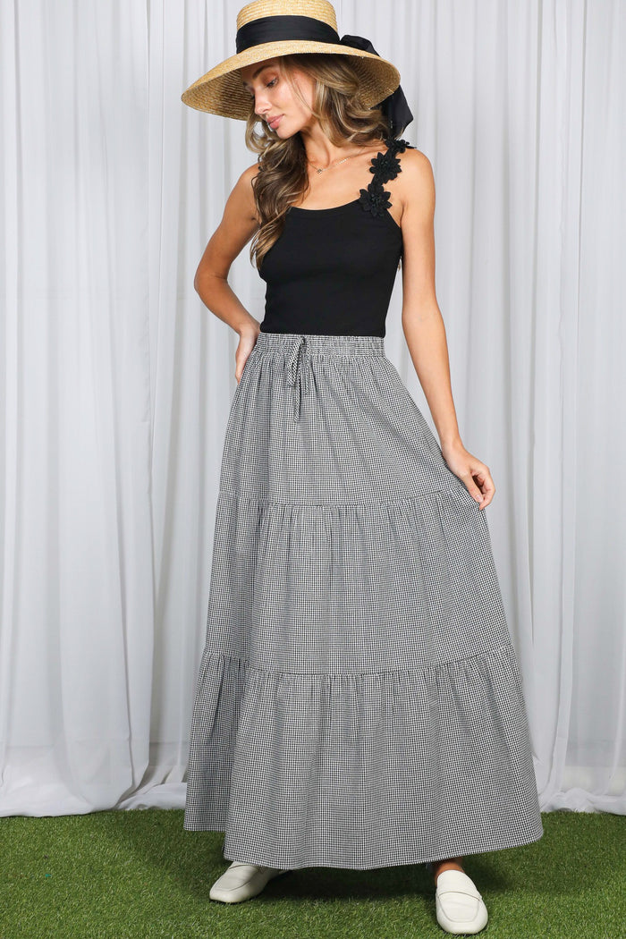 woman wearing a black tank top and a gray striped maxi skirt with tiers and a drawstring waist