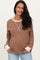 woman wearing a brown maternity pullover with white trim and a visible baby bump