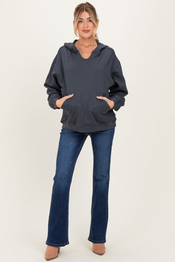 woman wearing a dark gray maternity hoodie with a v-neck and front pockets paired with flared jeans