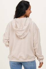 woman wearing a beige oversized maternity hoodie with a hood, shown from the back