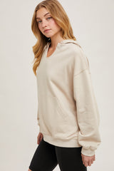 woman wearing a beige oversized hoodie with a front pocket and a drawstring hood, styled with black bike shorts