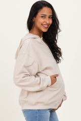 woman wearing a beige maternity hoodie with a front pocket and a visible baby bump