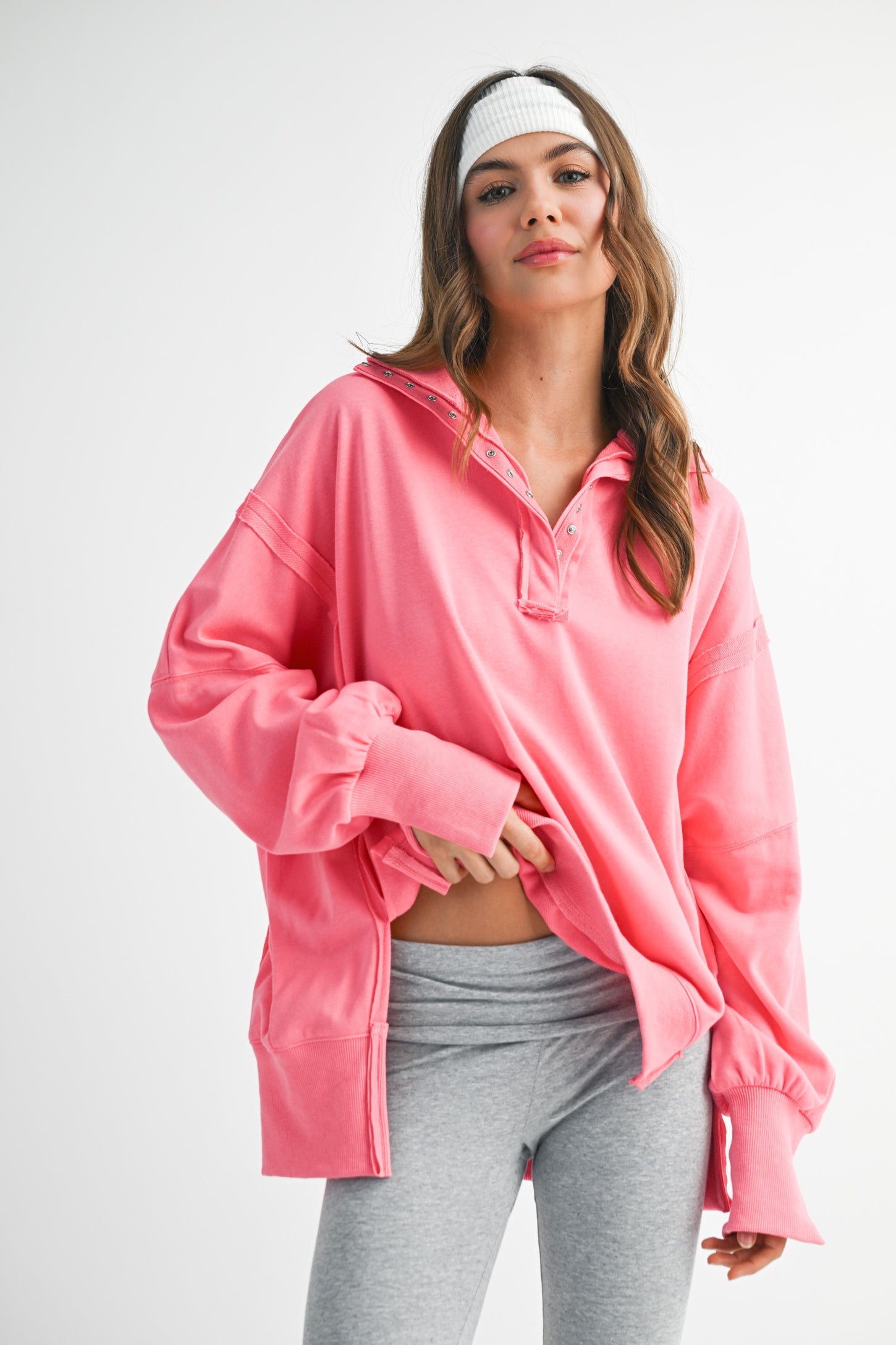 woman wearing a bright pink oversized pullover with a collar and long sleeves, paired with gray leggings