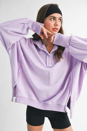 woman wearing a light purple oversized pullover sweatshirt with a henley collar and long sleeves
