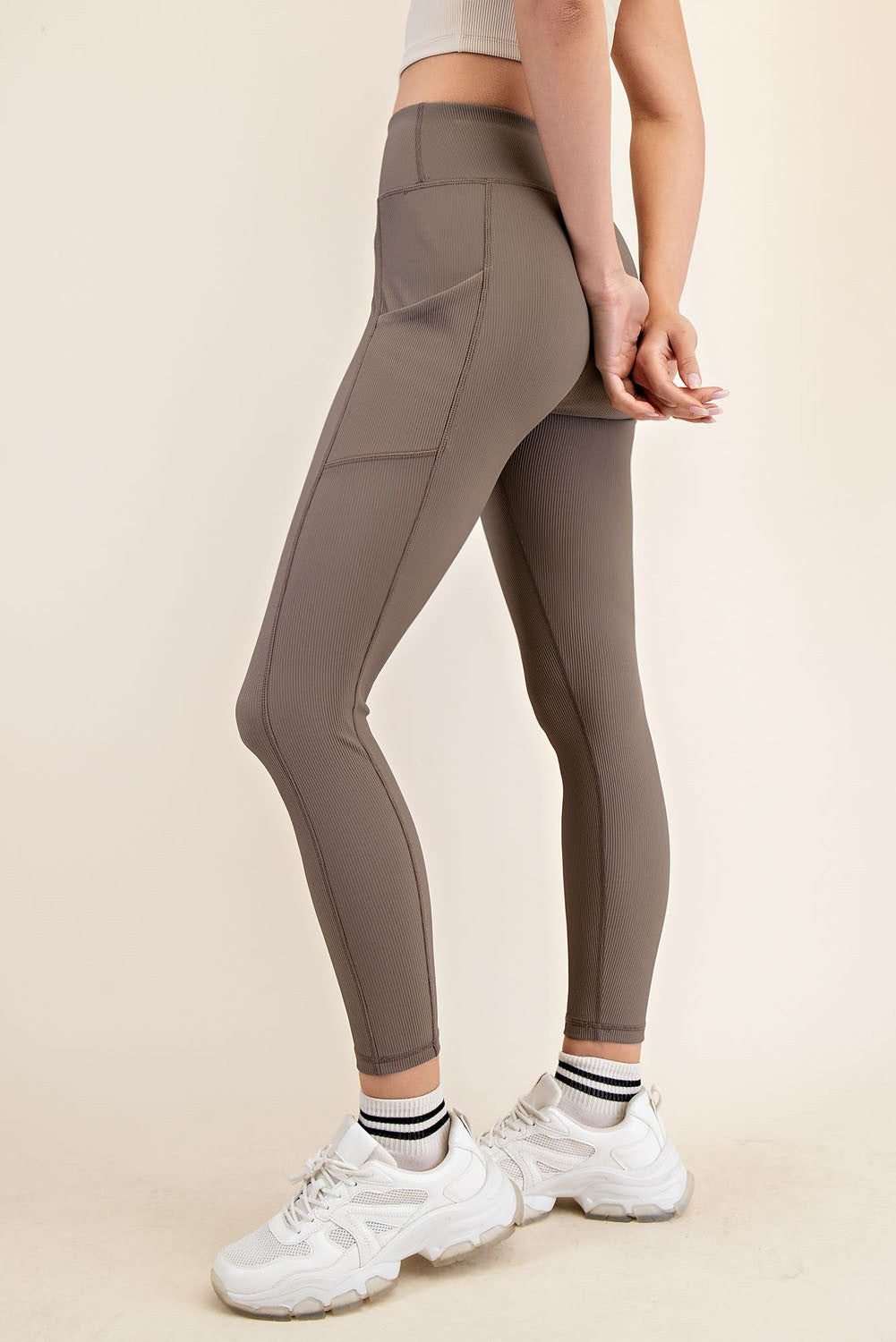 woman wearing brown high-waisted leggings with ribbed texture and paired with white sneakers