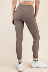 woman wearing light brown high-waisted leggings with a ribbed texture and side pockets, showing the back view