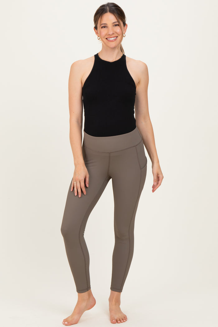 woman wearing a black halter neck maternity top and brown ribbed maternity leggings with side pockets