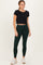 woman wearing a black cropped t-shirt and dark green leggings, paired with white athletic shoes