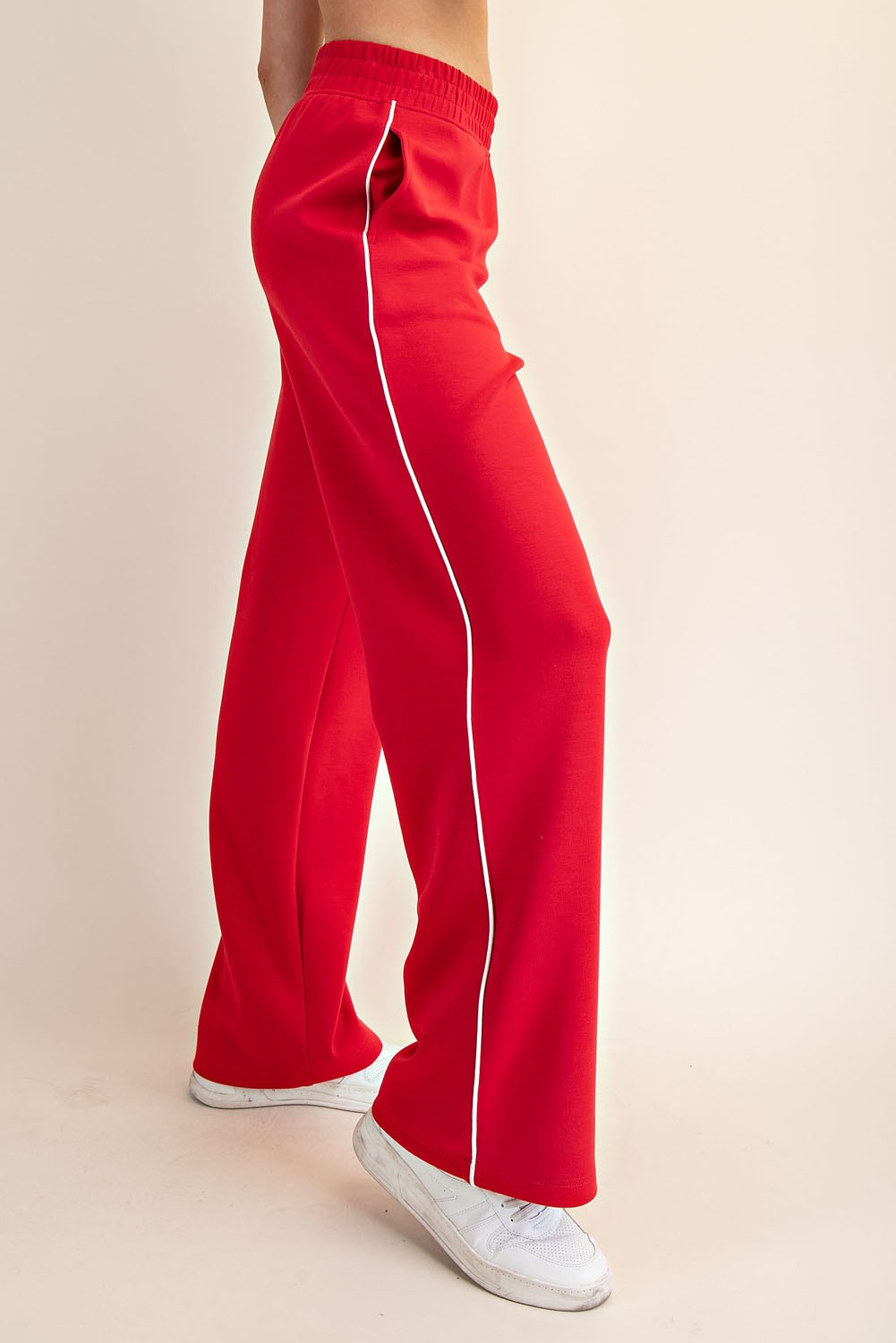 woman wearing bright red wide-leg pants with white side stripes and elastic waistband, styled with white sneakers