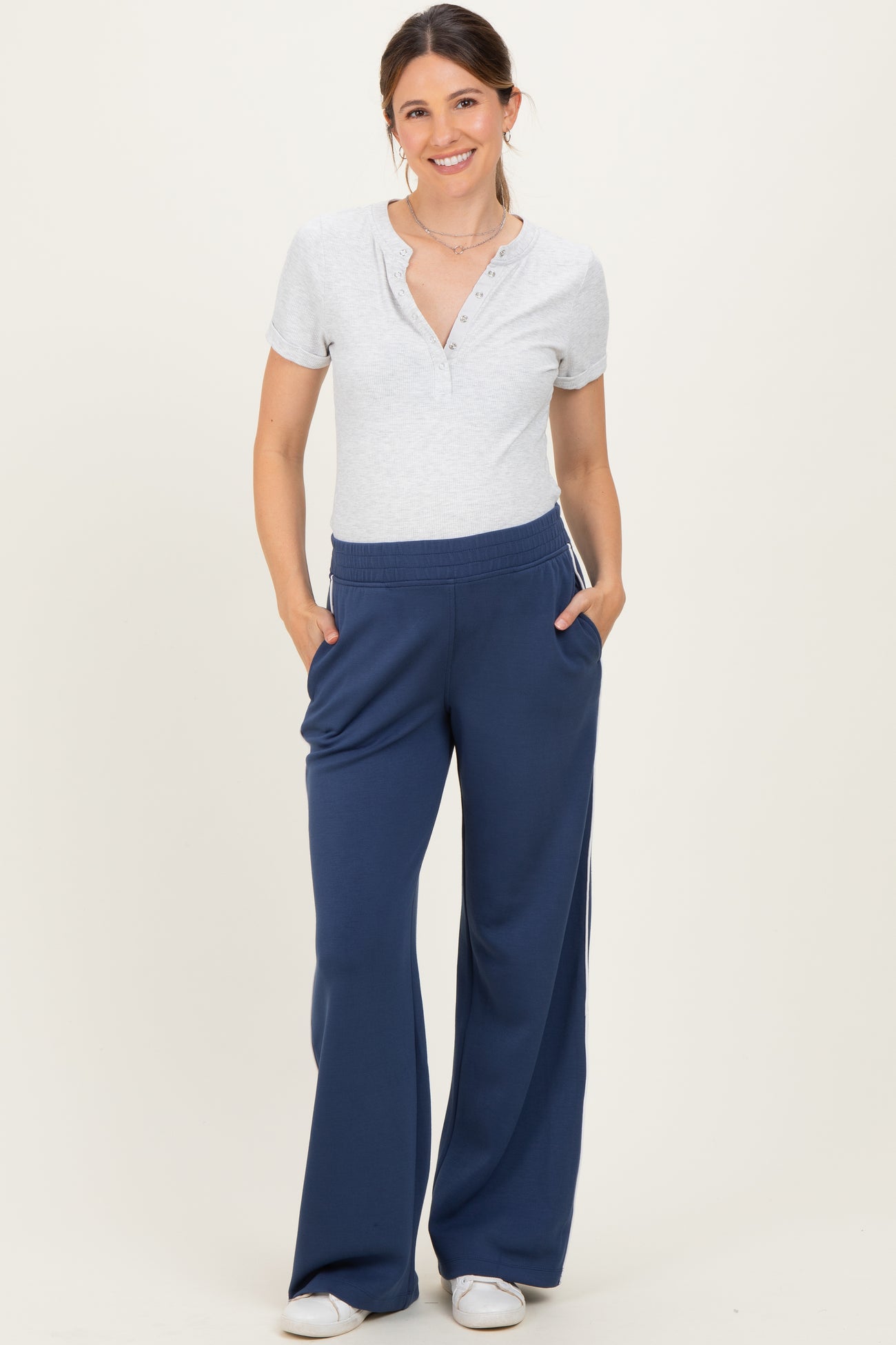 woman wearing a gray short sleeve henley top and navy blue maternity sweatpants with pockets