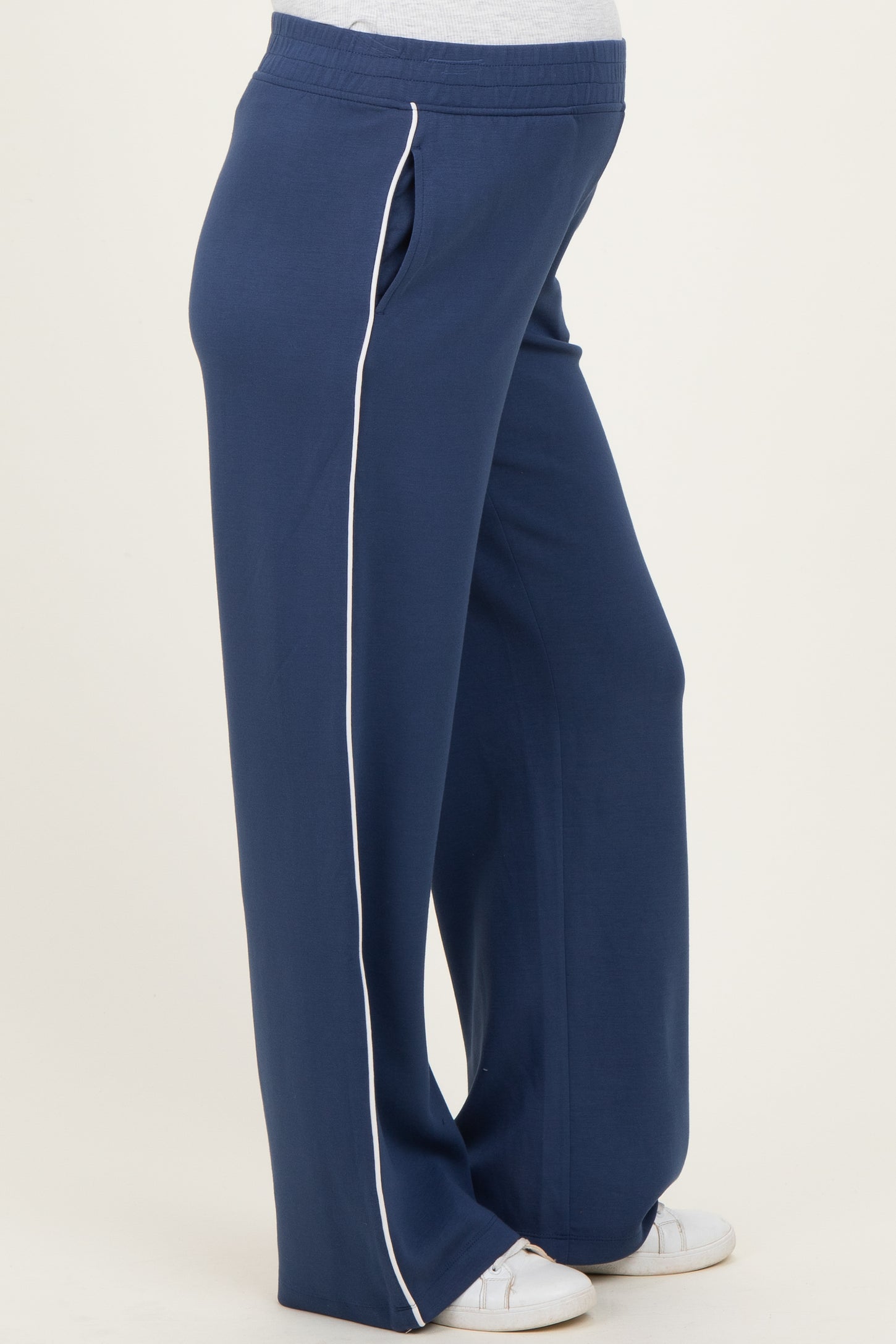 woman wearing navy blue maternity sweatpants with white side piping and a visible baby bump