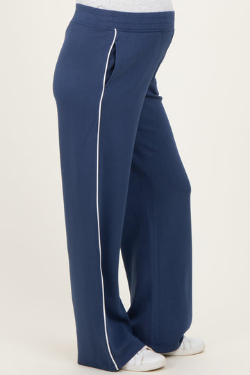 woman wearing navy blue maternity sweatpants with white side piping and a visible baby bump