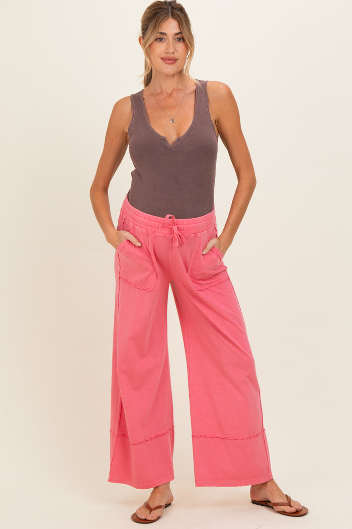 woman wearing a brown ribbed maternity tank top and coral pink wide-leg maternity pants with pockets