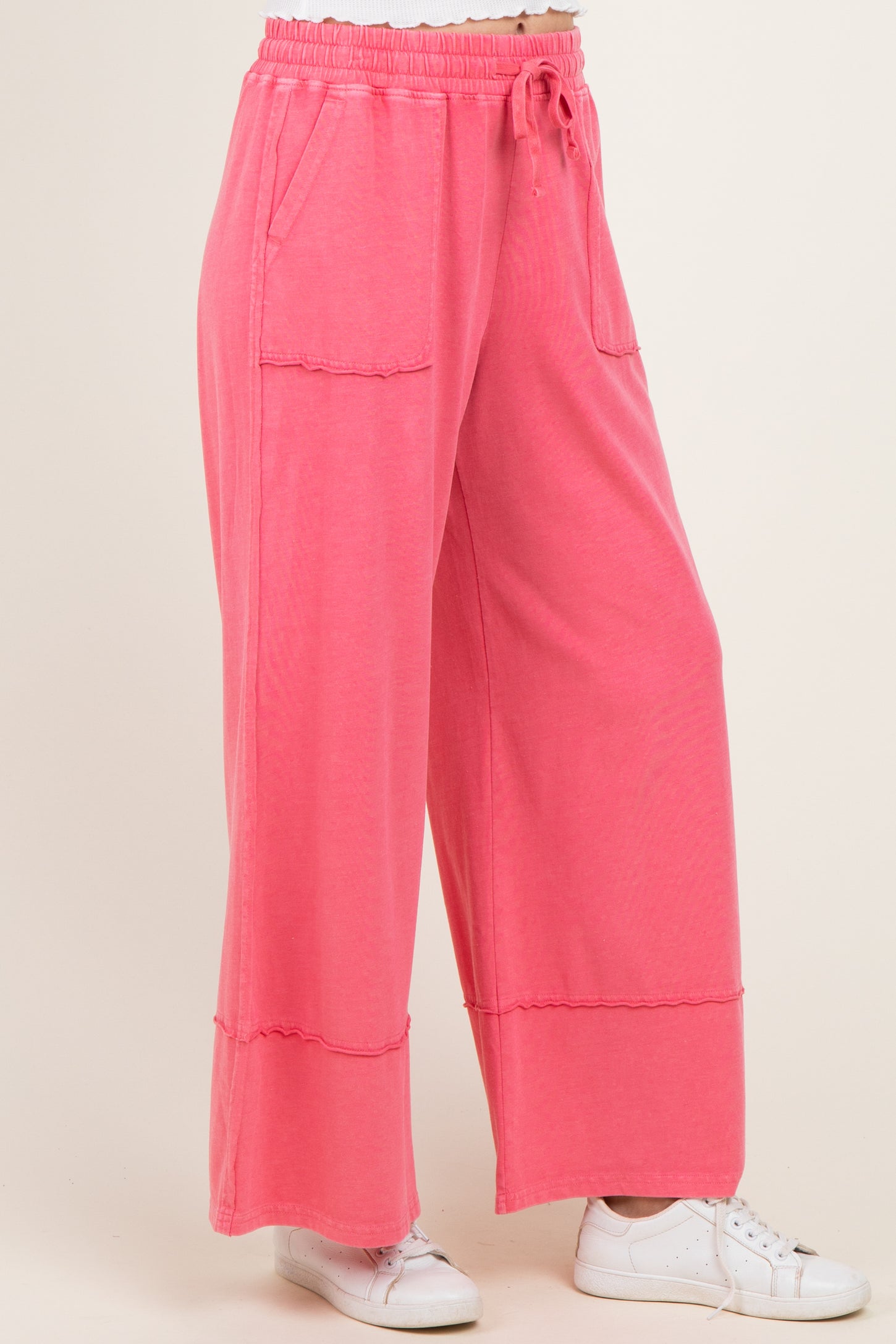 woman wearing pink wide leg lounge pants with pockets and drawstring waist, paired with white sneakers