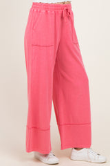 woman wearing pink wide leg lounge pants with pockets and drawstring waist, paired with white sneakers