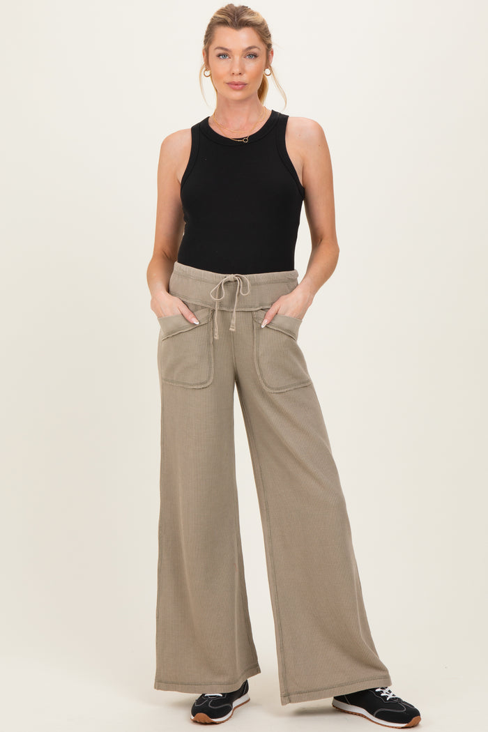 woman wearing a black sleeveless maternity top and beige wide leg pants with pockets
