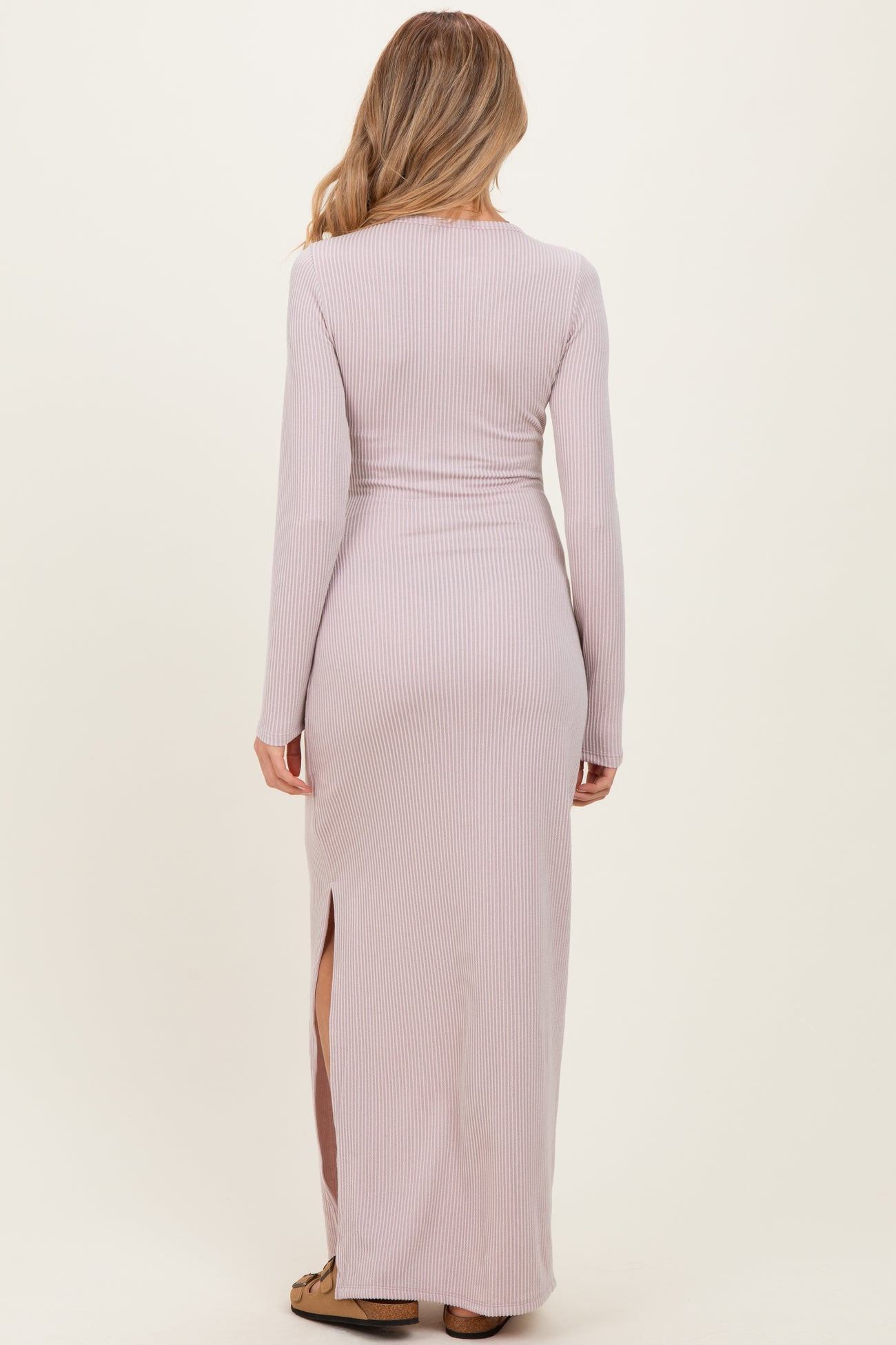 woman wearing a light pink long sleeve maternity dress with a fitted style and side slit