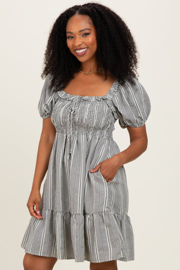 woman wearing a black and white checkered puff sleeve mini dress with a square neckline and pockets