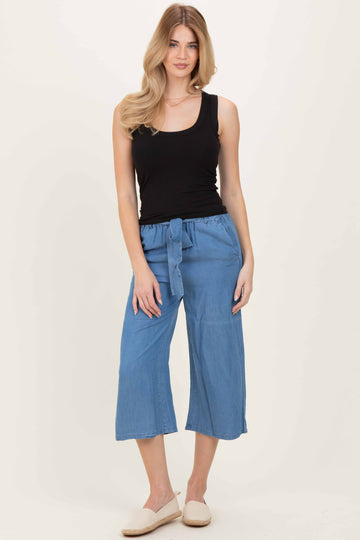 woman wearing a black ribbed tank top and light blue wide-leg cropped pants with a tie waistband