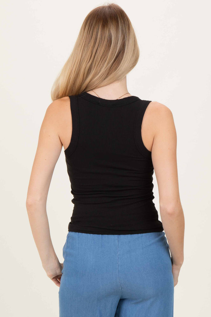 woman wearing a black ribbed tank top, seen from the back, paired with light blue pants