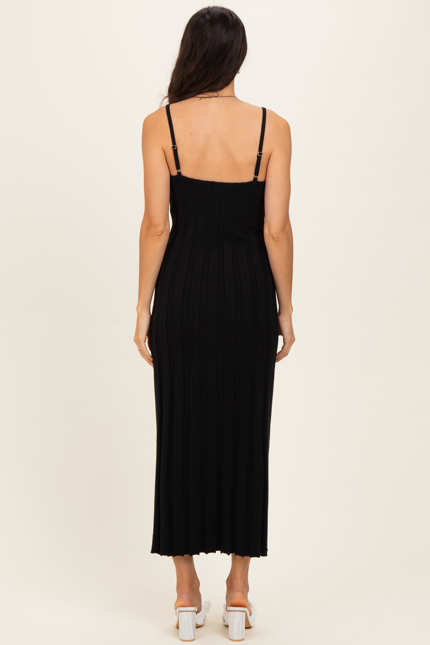woman wearing a black ribbed maxi dress with thin straps, viewed from the back