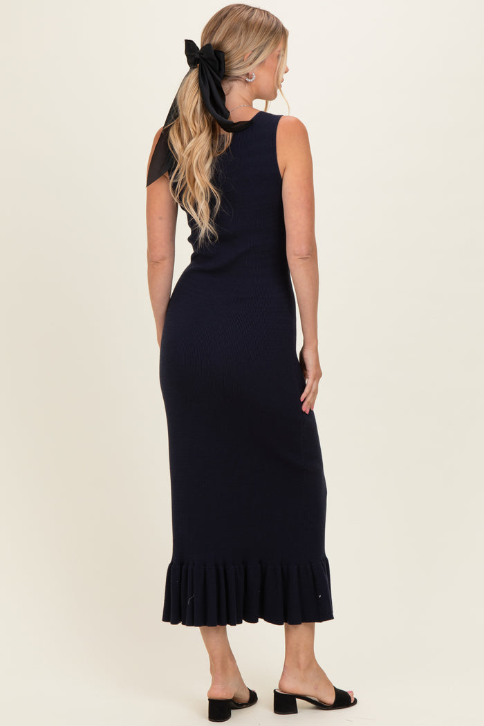 woman wearing a navy ribbed midi dress with a ruffled hem and a black hair bow, shown from the back