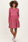 woman wearing a pink striped long sleeve maternity dress with a tiered skirt and holding her baby bump