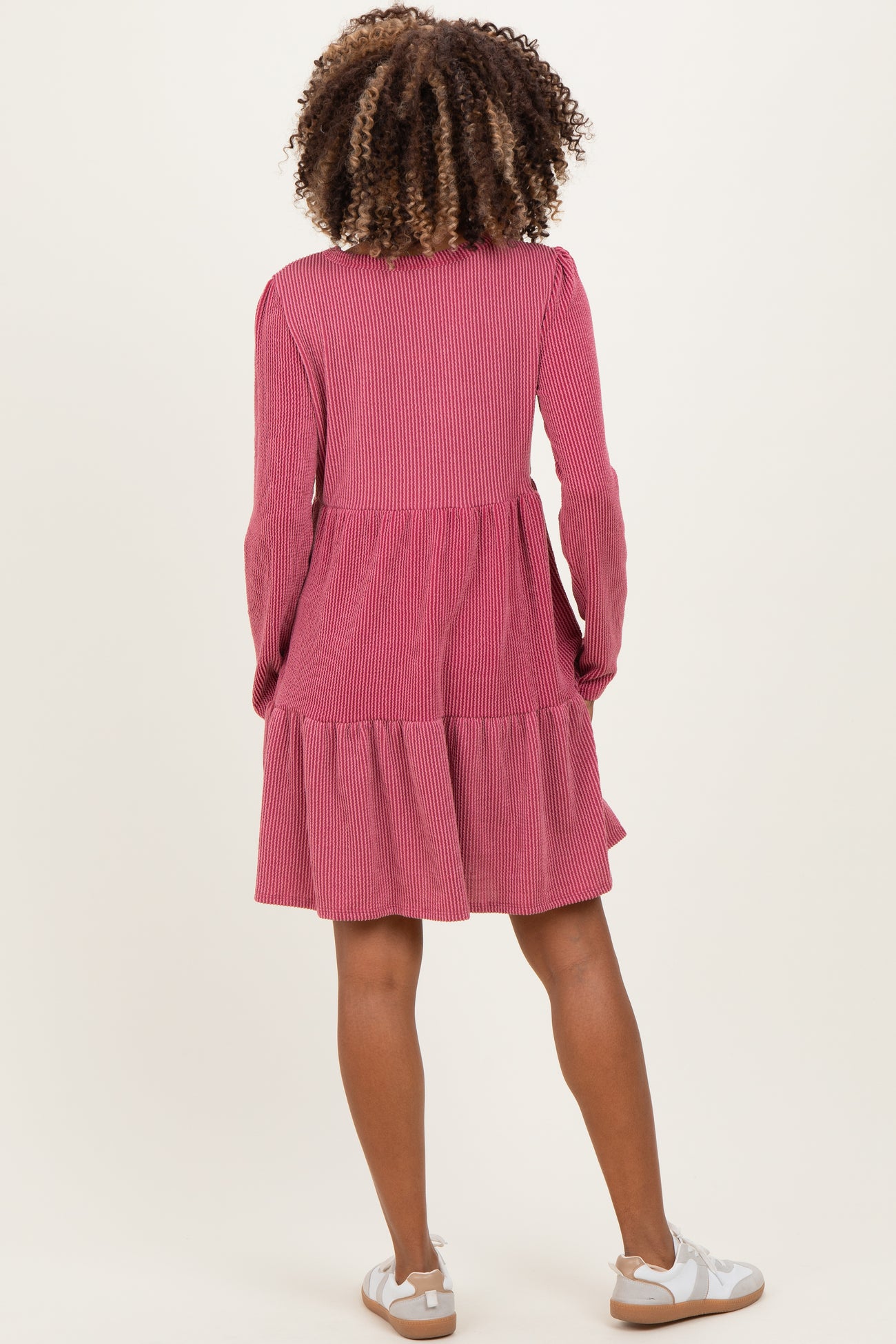 woman wearing a pink striped maternity dress with long sleeves and a tiered skirt, showing a baby bump from the back