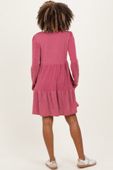 woman wearing a pink striped maternity dress with long sleeves and a tiered skirt, showing a baby bump from the back