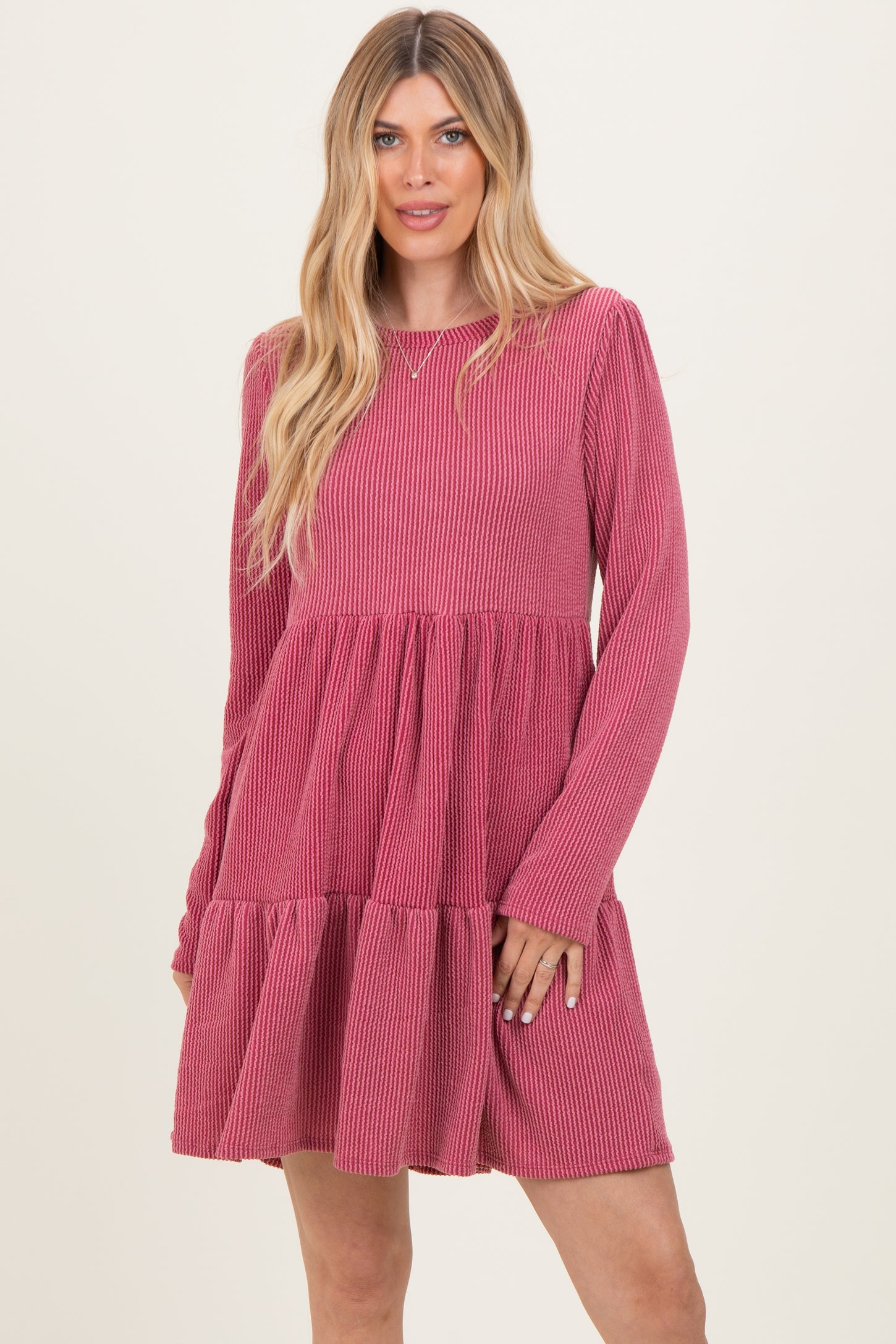 woman wearing a pink ribbed long sleeve dress with a tiered skirt and relaxed fit