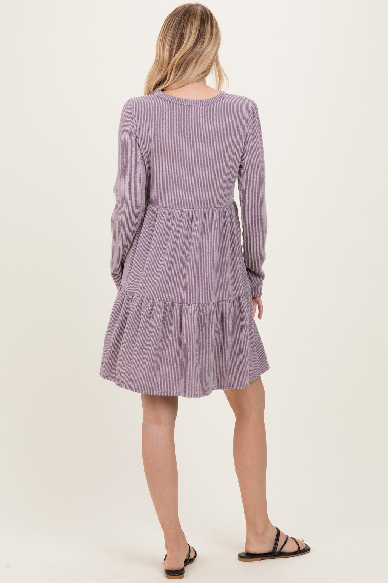 woman wearing a lavender striped long sleeve tiered dress, viewed from the back