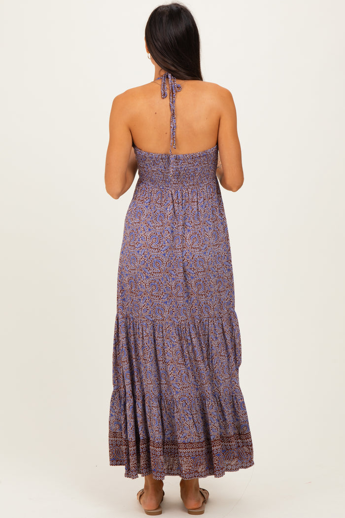 woman wearing a strapless purple printed maxi dress with smocked bodice and tiered skirt, seen from the back