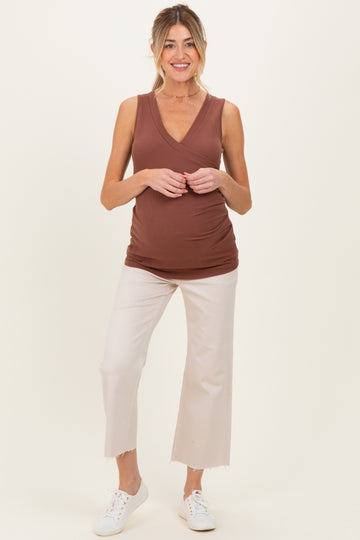 woman wearing a brown ribbed maternity tank top and white cropped pants, showcasing her baby bump