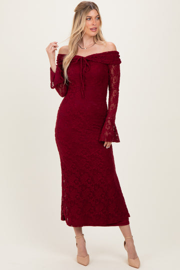 woman wearing a burgundy off-the-shoulder lace dress with bell sleeves and a fitted silhouette
